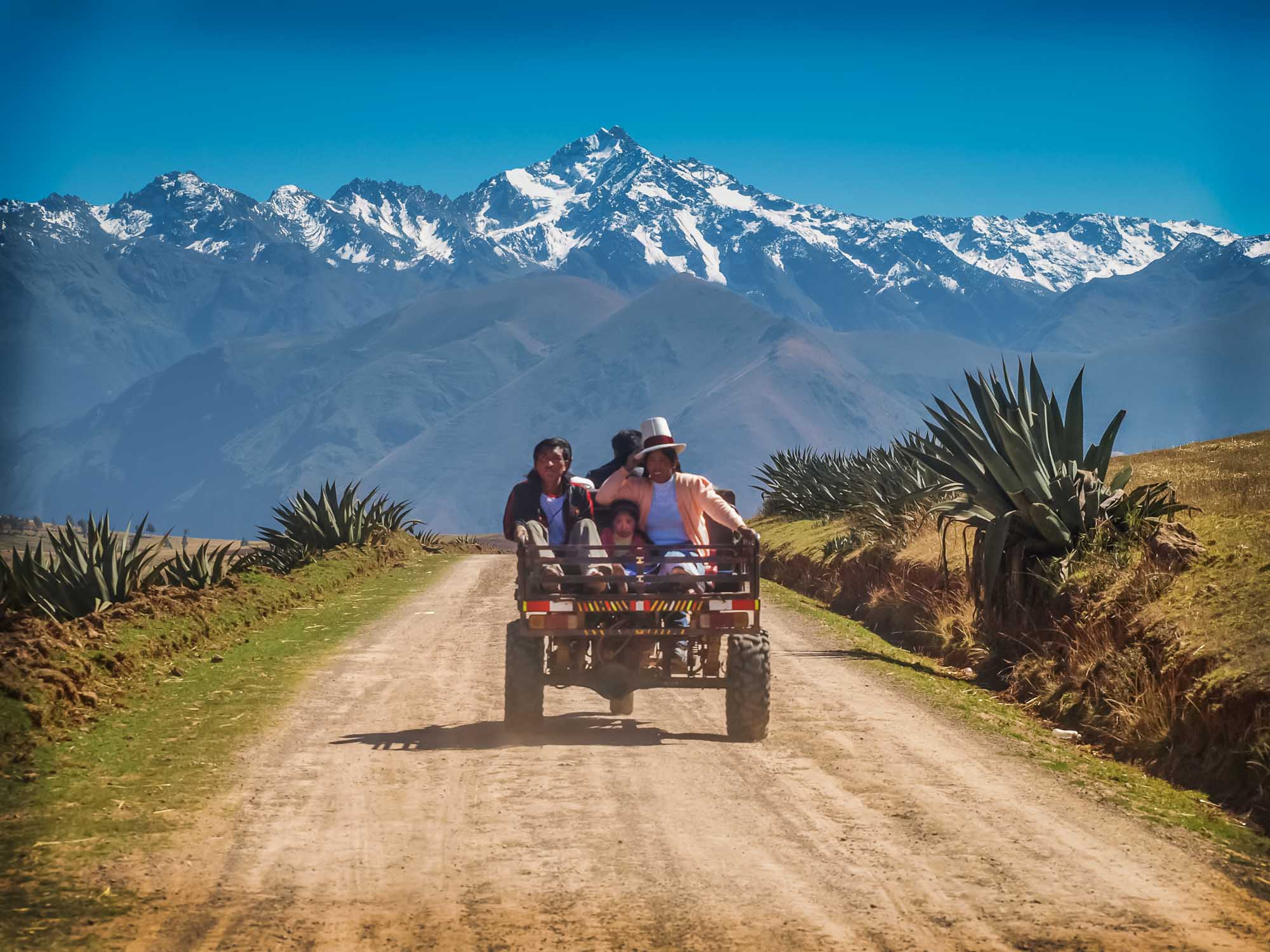 Peruvian family riding on the back of a tiny truck through a spectacular mountain landscape