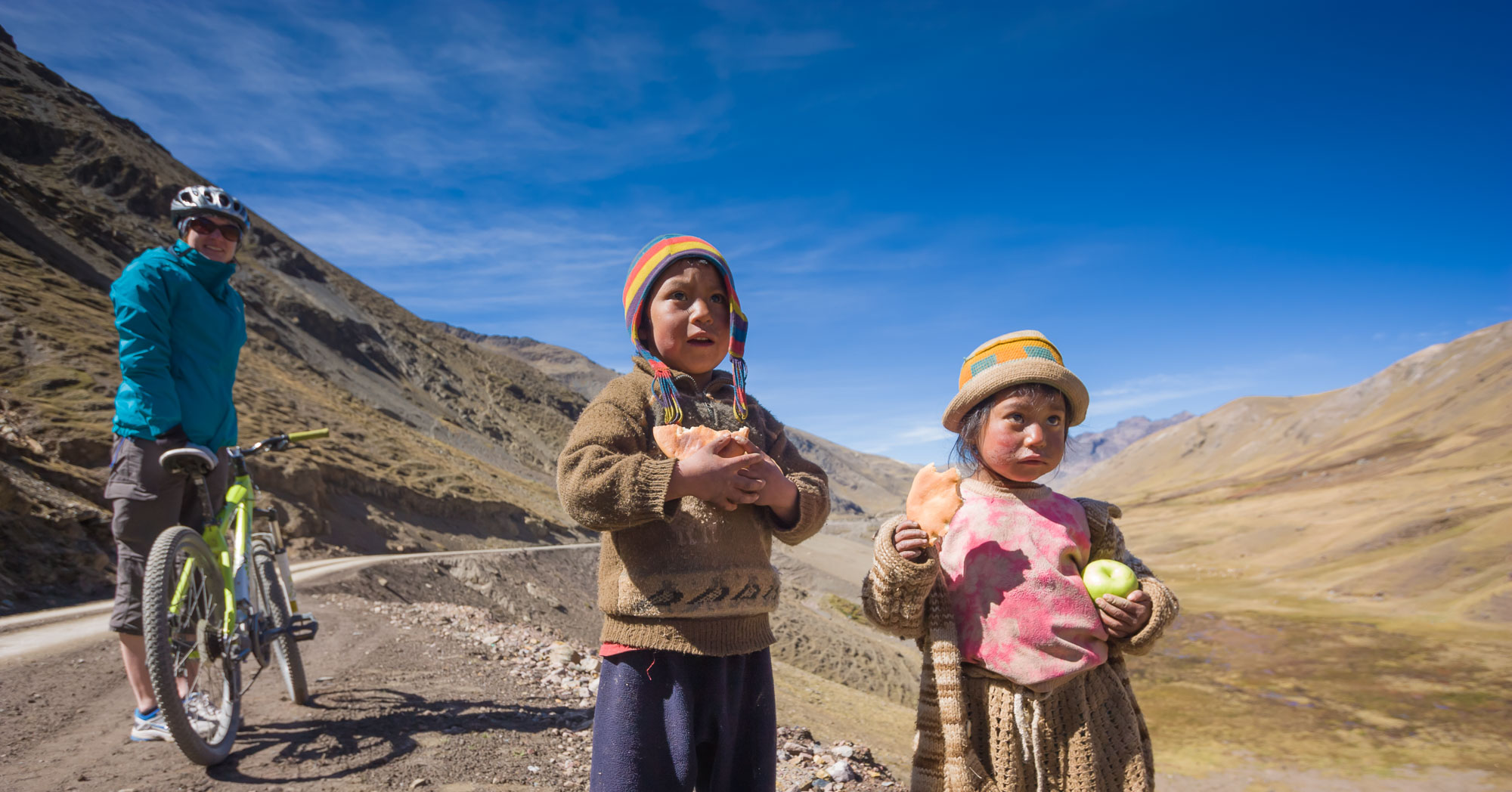 Guest on a Peru bike tour smiles at local children in the Lares valley