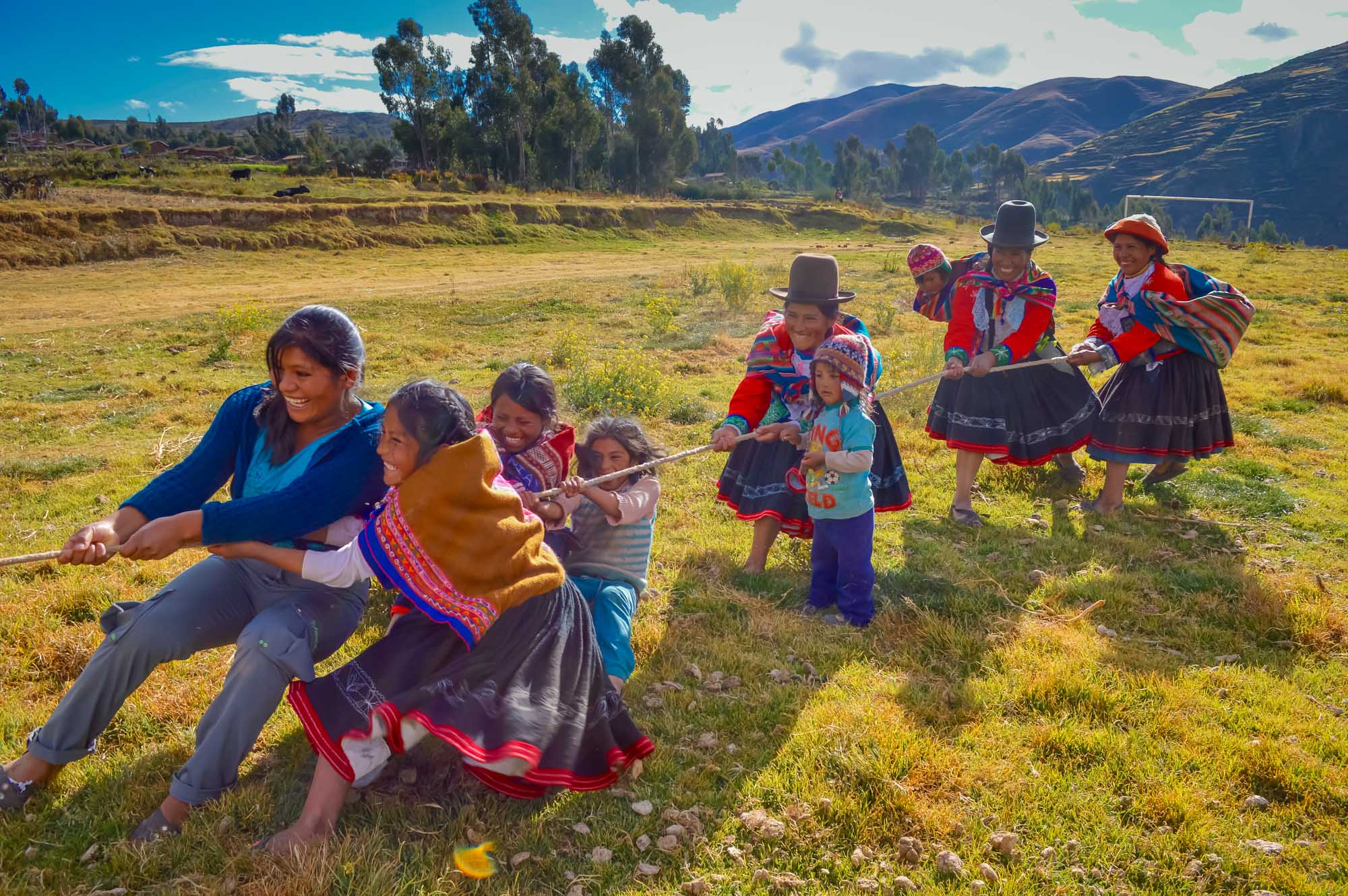 Laughing, traditionally dressed women and children play tug of war